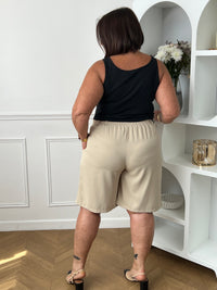 Bermuda beige grande taille pour femme, alliant confort et style pour la saison estivale. Équipé de deux poches latérales pratiques, d’une taille élastique au dos et de passants pour ceinture, il assure un ajustement parfait. Sa fermeture avec bouton et zip garantit un bon maintien. Polyvalent et facile à assortir, ce bermuda taupe est un indispensable du dressing casual chic.