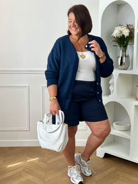 Découvrez le confort et le style avec le bermuda grande taille Charlize. Fait en tissu bleu foncé, il est doté de 2 poches latérales pratiques, d'une taille élastique et de passants pour ceinture