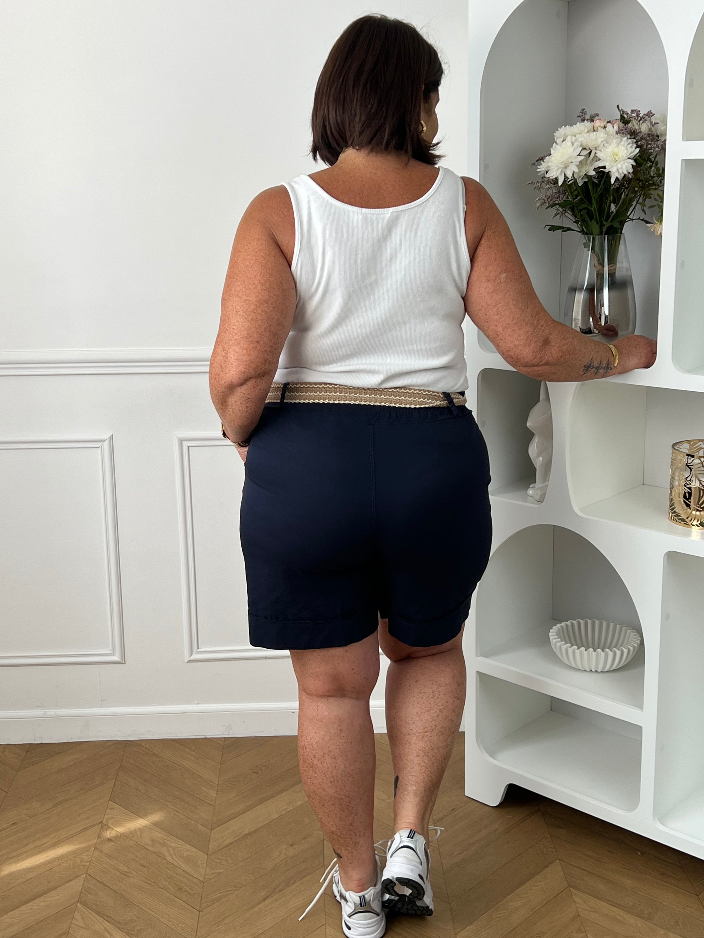 Découvrez le confort et le style avec le bermuda grande taille Charlize. Fait en tissu bleu foncé, il est doté de 2 poches latérales pratiques, d'une taille élastique et de passants pour ceinture