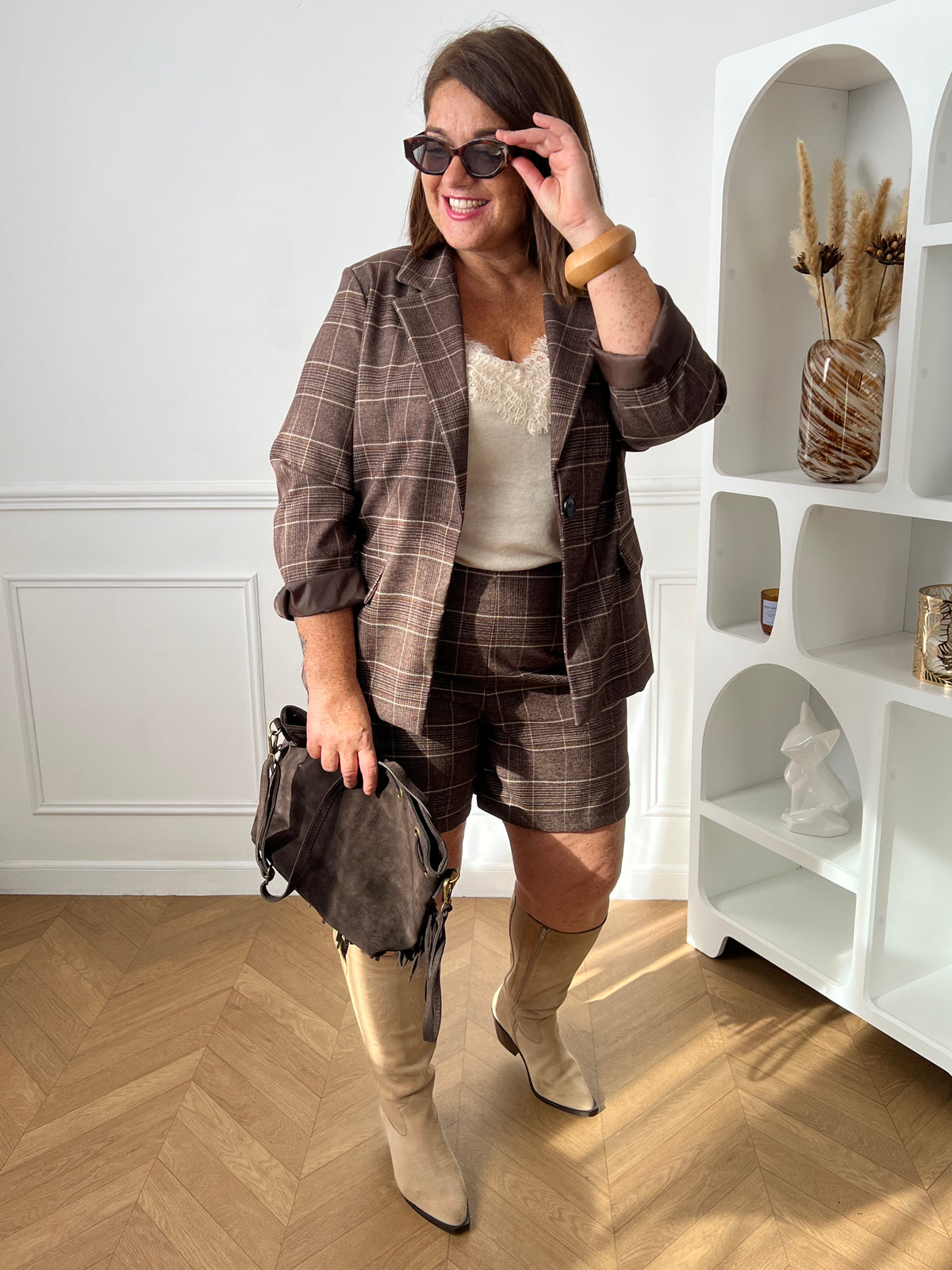Blazer marron à carreaux porté avec le short assorti, un top écru et des bottes hautes beiges – Yohan | Loïcia 