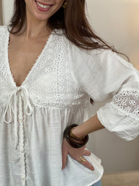 Blouse blanche pour femme, élégante et intemporelle, idéale pour toutes les occasions.
Dotée de manches longues, d’un col V et de délicates broderies sur le devant et les manches.
Ses détails avec boutons factices, lien et poignets élastiques apportent une touche raffinée.
Confectionnée en 100 % coton, elle offre confort et légèreté au quotidien.