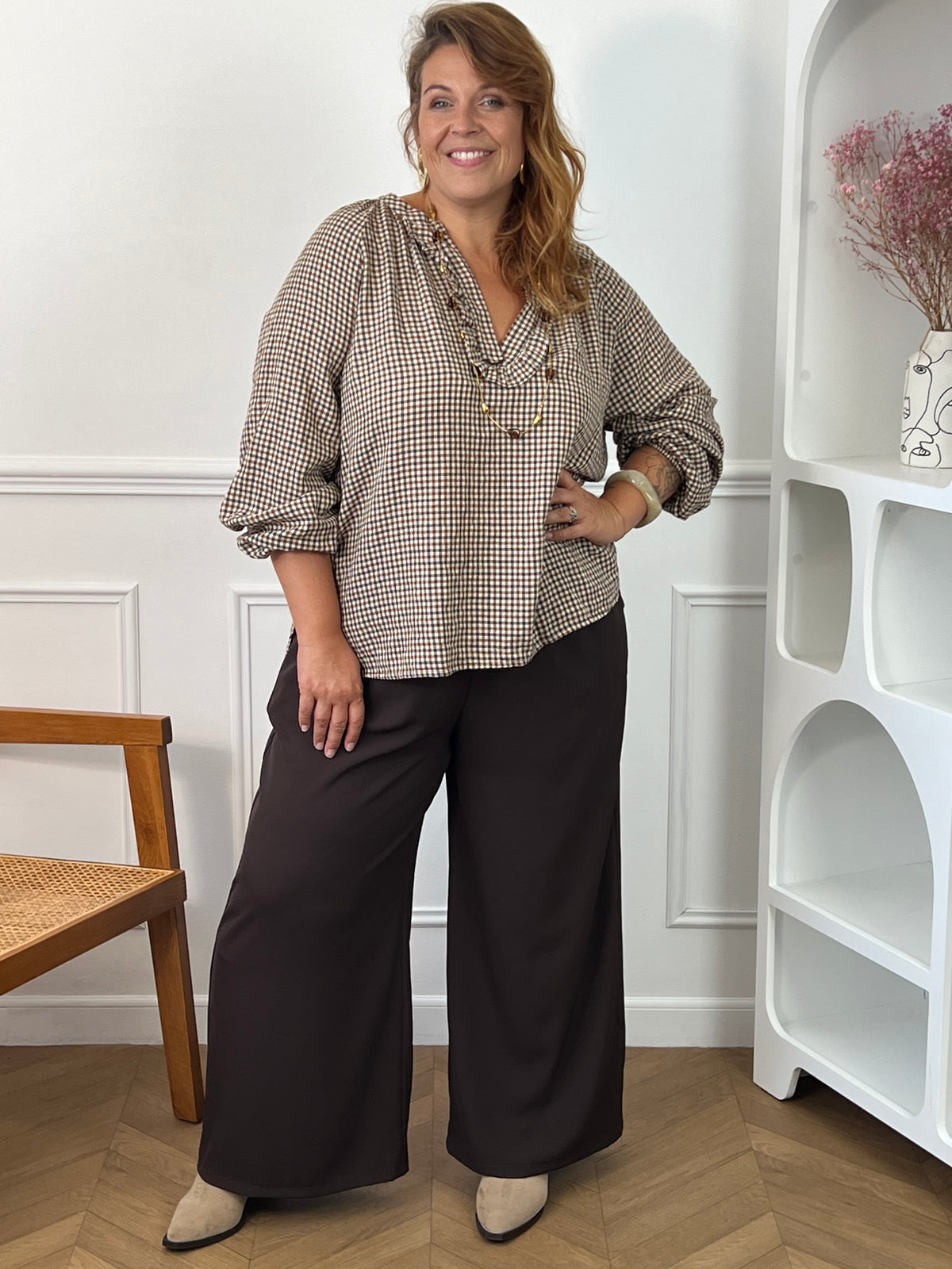 Blouse à carreaux Nour grande taille portée de face avec un pantalon large foncé, montrant sa coupe ample et ses manches retroussées.