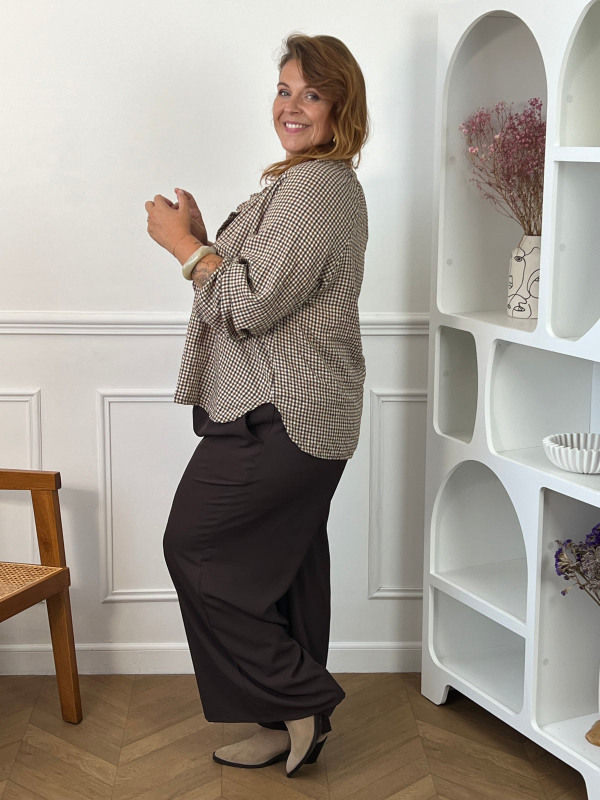 Blouse Nour à carreaux portée de profil, montrant sa coupe ample et son bas arrondi plus long dans le dos.