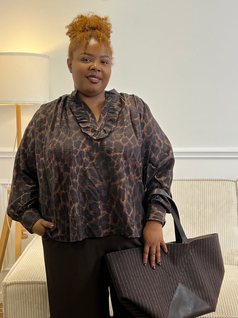 Blouse léopard grande taille à encolure volantée et manches longues, portée avec un pantalon foncé et un sac cabas – Hanna | Loïcia