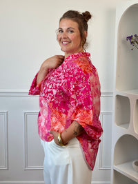 Vue de profil de la blouse fuchsia grande taille, plus longue à l’arrière pour un tombé fluide.