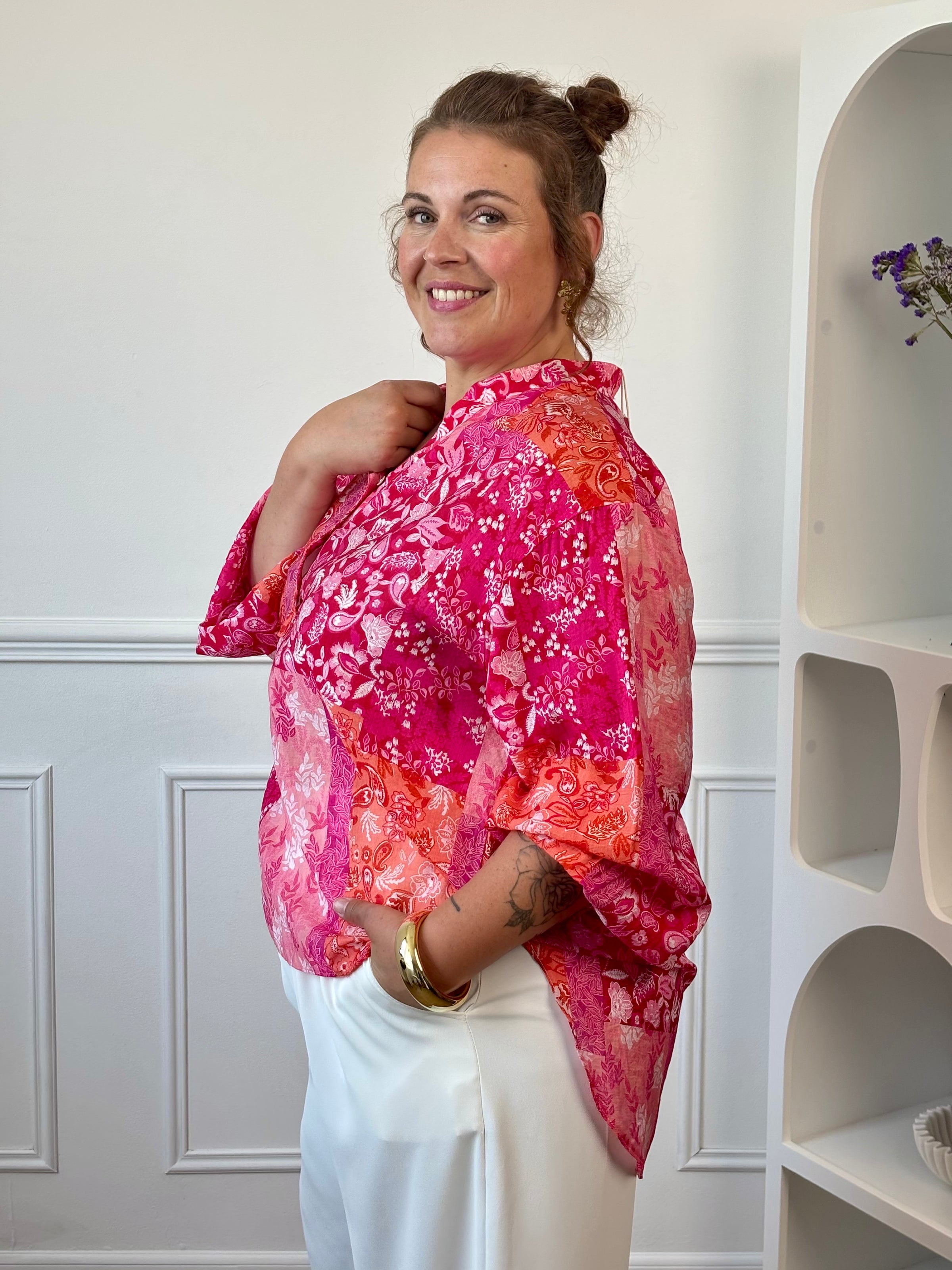Vue de profil de la blouse fuchsia grande taille, plus longue à l’arrière pour un tombé fluide.