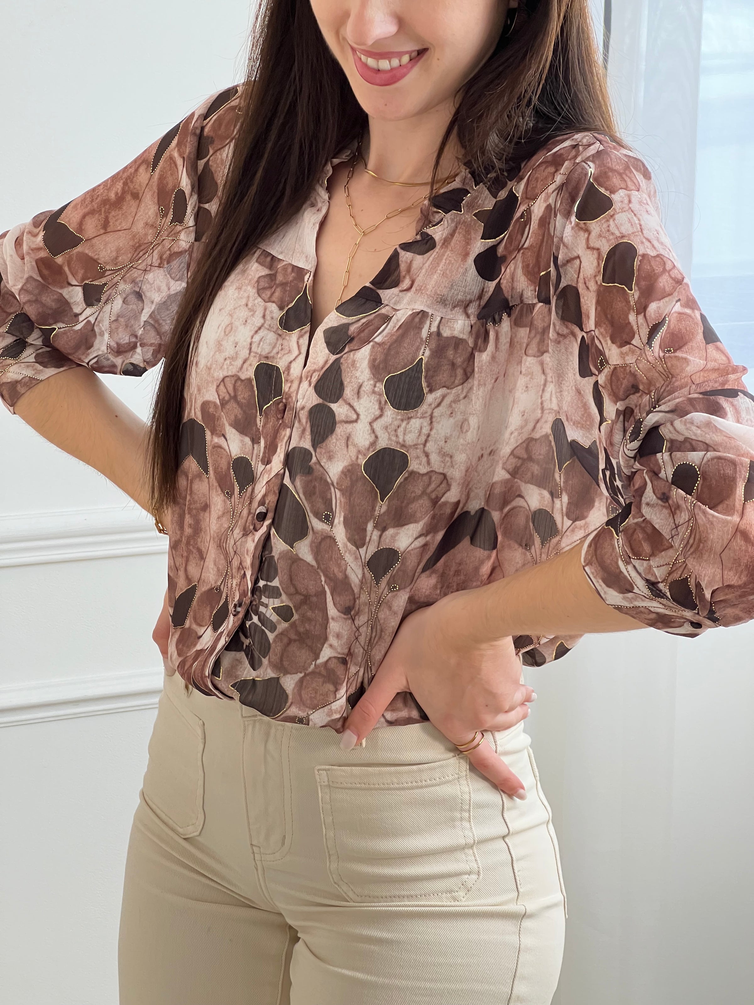 La chemise Elma en marron offre style et confort pour les femmes. Avec ses manches longues, son col V à volants et son motif floral rehaussé de lurex doré, elle conjugue élégance et féminité. Doublée de la poitrine au bas et fermée par des boutons.