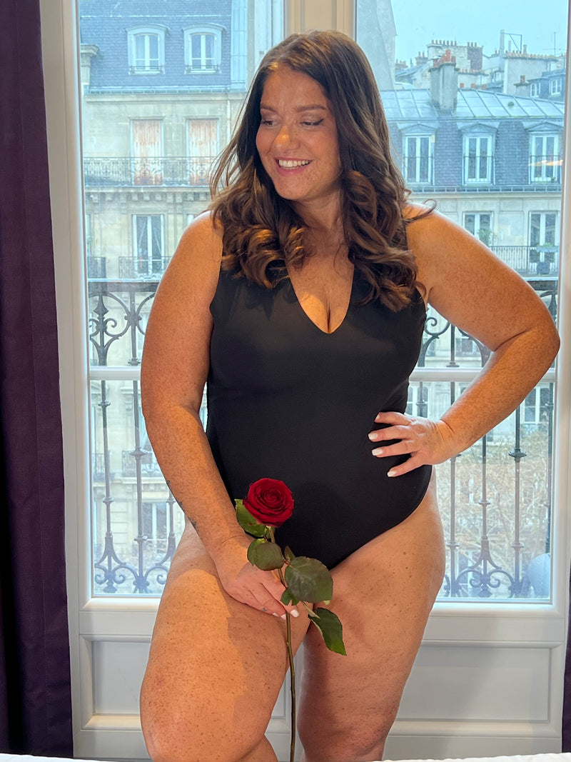 Body noir grande taille conçu pour sublimer votre silhouette avec élégance. Coupe sans manches et col V qui affine la ligne, agrémentée de légers plis latéraux pour un confort optimal. Fermeture par attache crochets pratique et discrète. Pièce incontournable en noir pur, parfaite pour créer des looks épurés et intemporels.