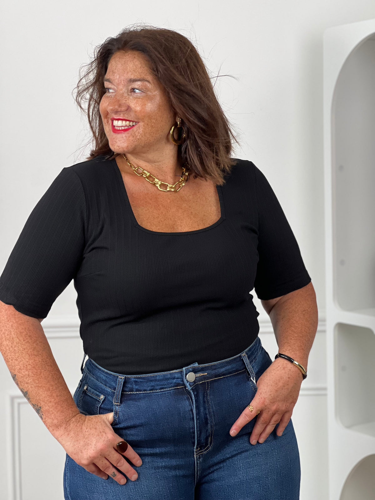 Top noir côtelé col carré manches courtes grande taille - détail buste avec jean brut taille haute, collier chaîne dorée et boucles d'oreilles dorées