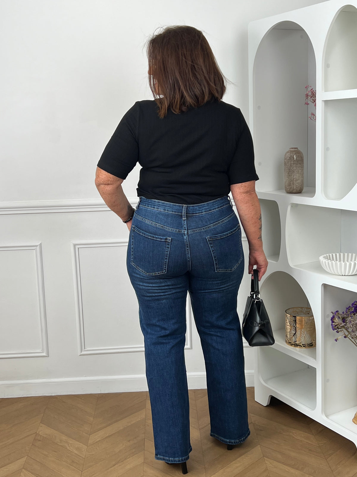 Top noir manches courtes grande taille - vue de dos avec jean wide leg brut taille haute et sac à main noir - coupe ajustée et féminine