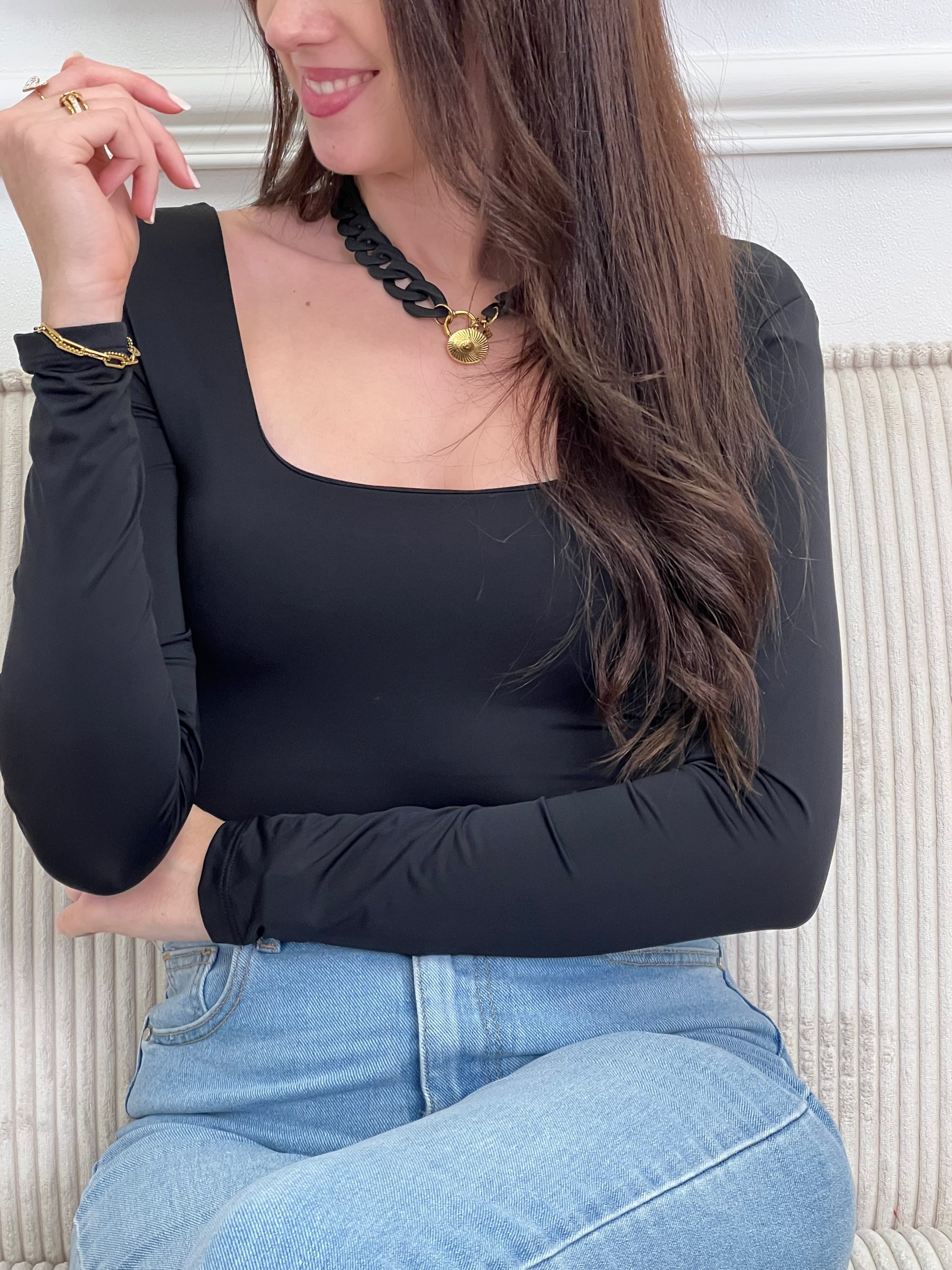 Body noir élégant aux manches longues et col carré. Fermeture pratique avec accroche crochet pour un ajustement sur mesure. Un incontournable polyvalent à porter seul ou en superposition.