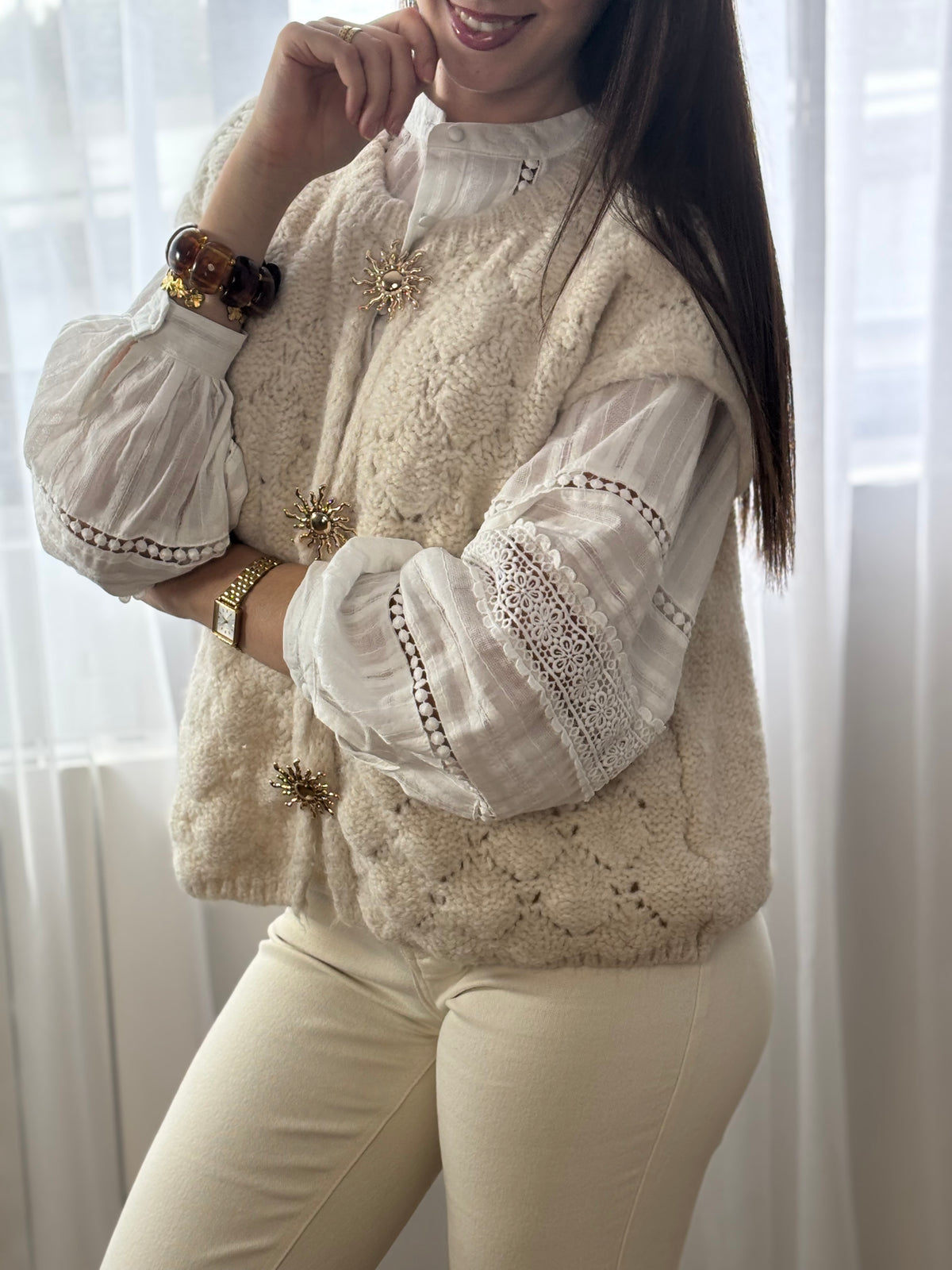 Ce gilet sans manches beige, Gaela, allie simplicité et élégance avec son col rond classique. Les broches dorées sur le devant ajoutent une touche sophistiquée, rehaussant discrètement votre look tout en restant confortable et facile à porter.