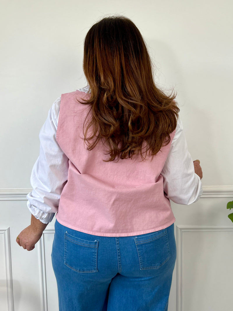 Un vrai bijou de douceur : cette veste rose sans manches séduit par sa coupe élégante et ses délicates broderies écru. Parfaite pour sublimer une tenue en toute légèreté avec une touche de charme bohème.