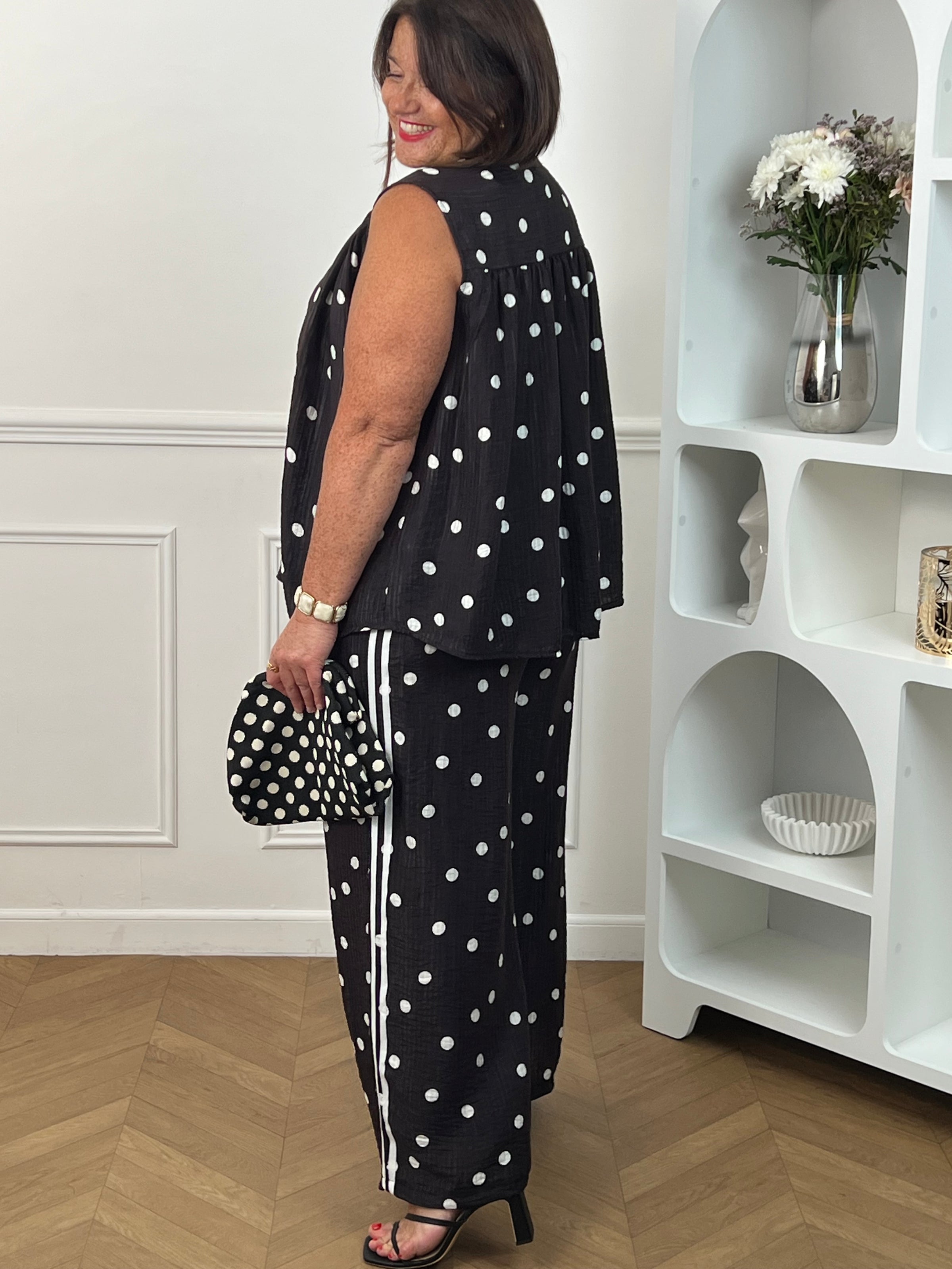 Adoptez un style à la fois tendance et confortable avec ce pantalon large noir grande taille à motifs pois écrus. Sa taille élastiquée assure un ajustement parfait, tandis que sa coupe fluide offre une grande liberté de mouvement. Les rayures écrues sur les côtés apportent une touche moderne et élancent la silhouette. Doté de poches latérales pratiques et confectionné dans une matière légèrement transparente, ce pantalon noir et écru est idéal pour composer des looks élégants et décontractés.