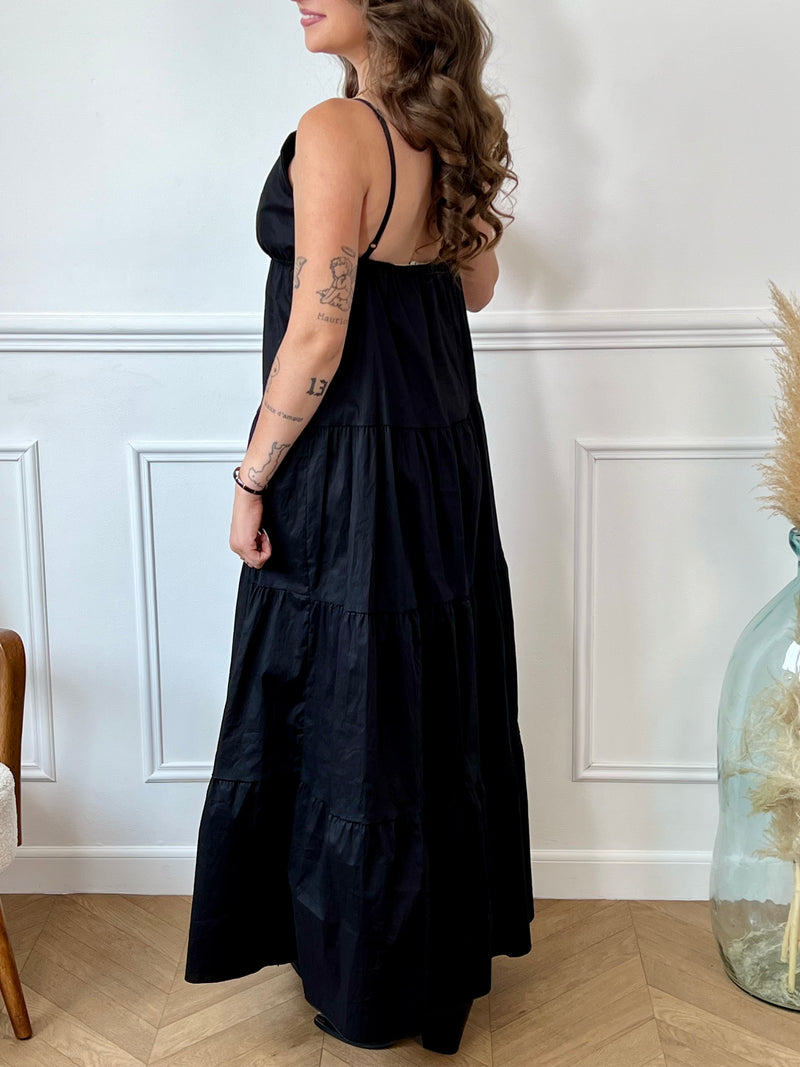 Cette robe longue noire, Elenora, allie élégance et confort grâce à ses bretelles réglables et sa taille élastique qui s’adaptent parfaitement à votre silhouette. Son col en V met en valeur le décolleté, tandis que le détail doré en forme de soleil apporte une touche lumineuse et raffinée sur la poitrine.