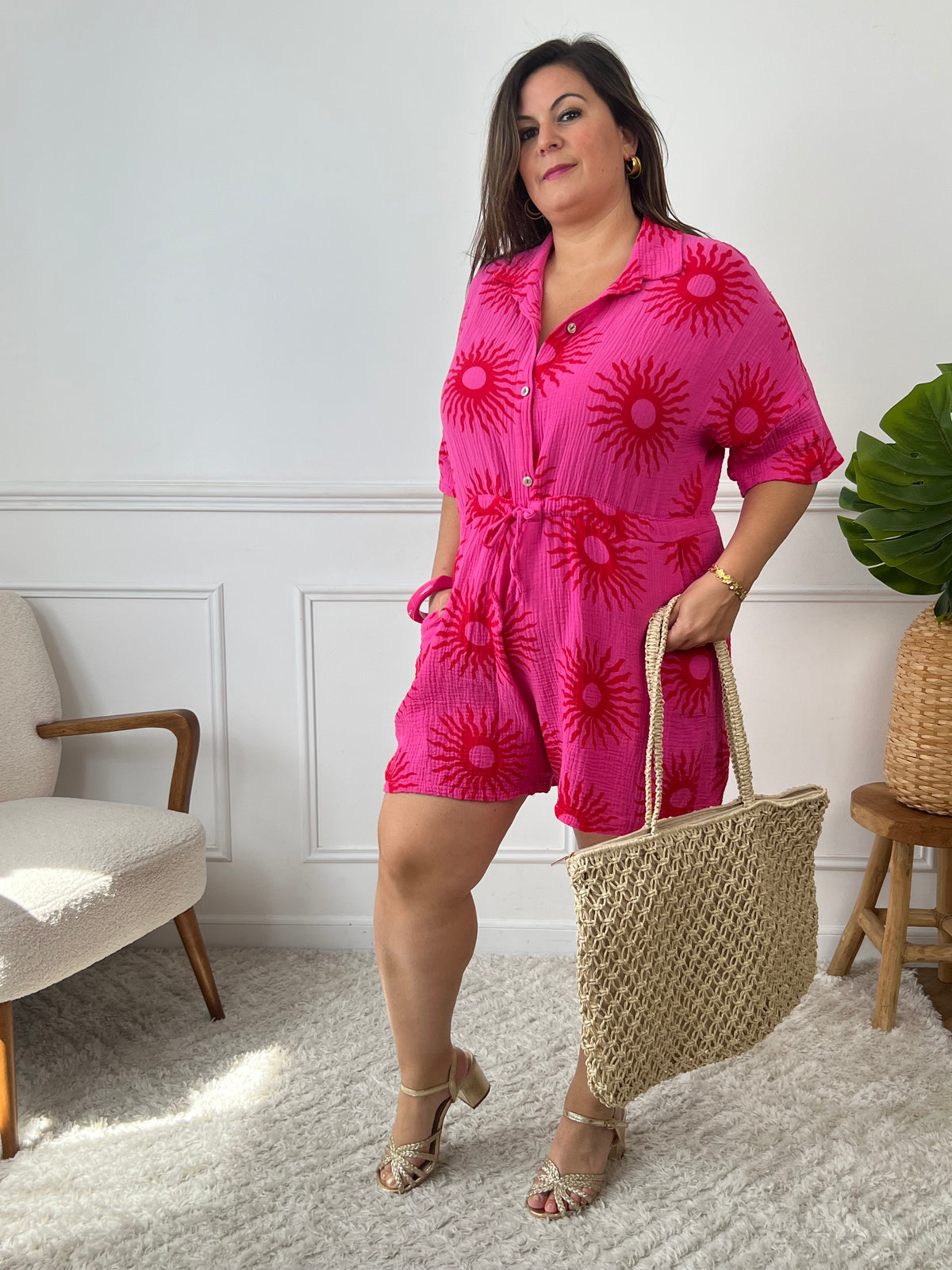 Découvrez notre Combishort fuchsia grande taille "Alyana" en gaze de coton, idéale pour l'été! Le motif soleil rouge sur le fond fuchsia ajoute une touche de pep's, et les poches latérales et le lien à nouer à la taille offrent confort et style.