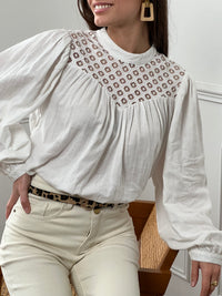 Cette blouse écrue en 100% coton pour femme allie élégance et raffinement avec ses détails ajourés et ses broderies délicates. Conçue avec des manches longues et un col rond, elle présente un bouton discret au dos pour une touche d'originalité. La blouse est doublée à l'avant pour un confort optimal, tandis que les détails ajourés ajoutent une note de sophistication. Sa teinte écrue douce et naturelle s’accorde facilement avec différents styles, idéale pour un look chic et intemporel. Cette blouse en coton 