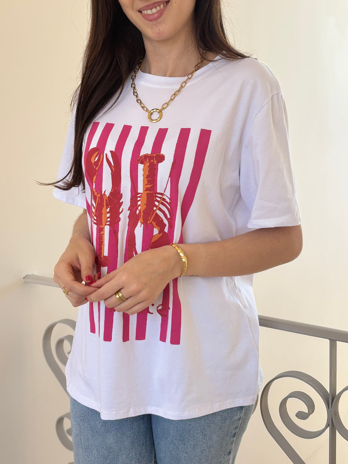 Le tee-shirt écru Adelina offre un col V et manches courtes, avec des motifs homards et traits fuchsia pour une touche colorée et originale.
