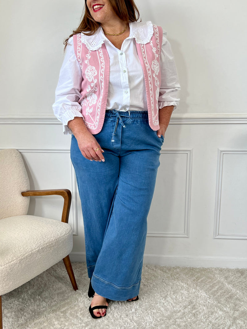 Un vrai bijou de douceur : cette veste rose sans manches séduit par sa coupe élégante et ses délicates broderies écru. Parfaite pour sublimer une tenue en toute légèreté avec une touche de charme bohème.