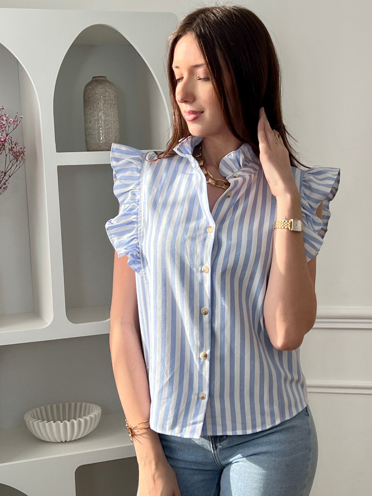 Adoptez cette chemise bleue et écrue femme sans manches, légère et élégante. Elle se ferme par des boutons sur toute la longueur et se distingue par ses volants au col et aux épaules, apportant une touche féminine. Ses rayures verticales en bleu et écru allongent la silhouette et subliment vos tenues.