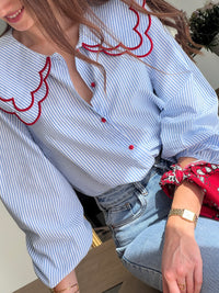 Chemise femme bleue à rayures avec col claudine, parfaite pour un look élégant et féminin. Ses manches longues et ses boutons rouges sur toute la longueur apportent une touche originale et raffinée. L’association des couleurs bleu, blanc et rouge crée un style chic et intemporel. Idéale pour une tenue moderne, aussi bien au bureau qu’au quotidien.