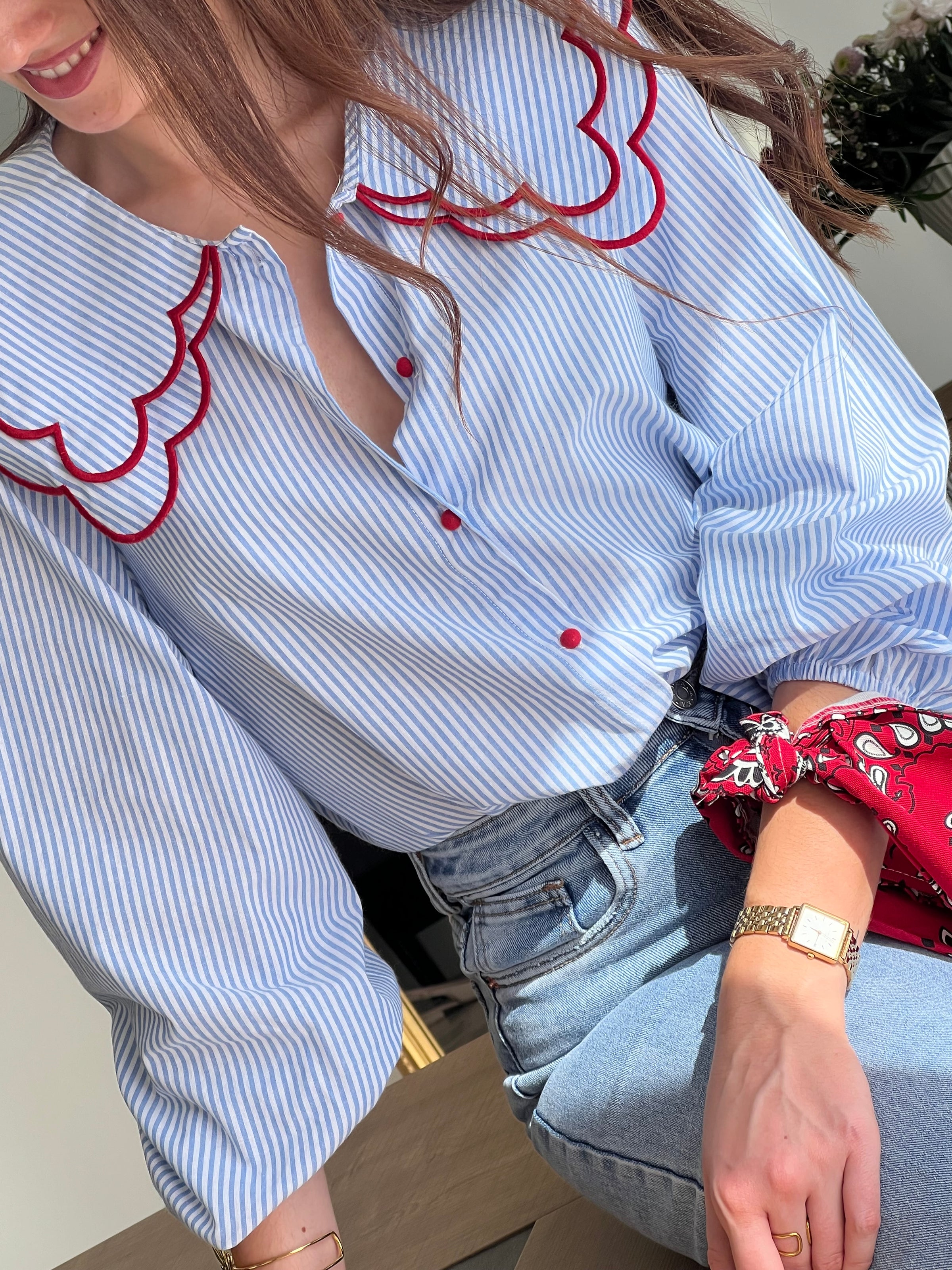 Chemise femme bleue à rayures avec col claudine, parfaite pour un look élégant et féminin. Ses manches longues et ses boutons rouges sur toute la longueur apportent une touche originale et raffinée. L’association des couleurs bleu, blanc et rouge crée un style chic et intemporel. Idéale pour une tenue moderne, aussi bien au bureau qu’au quotidien.