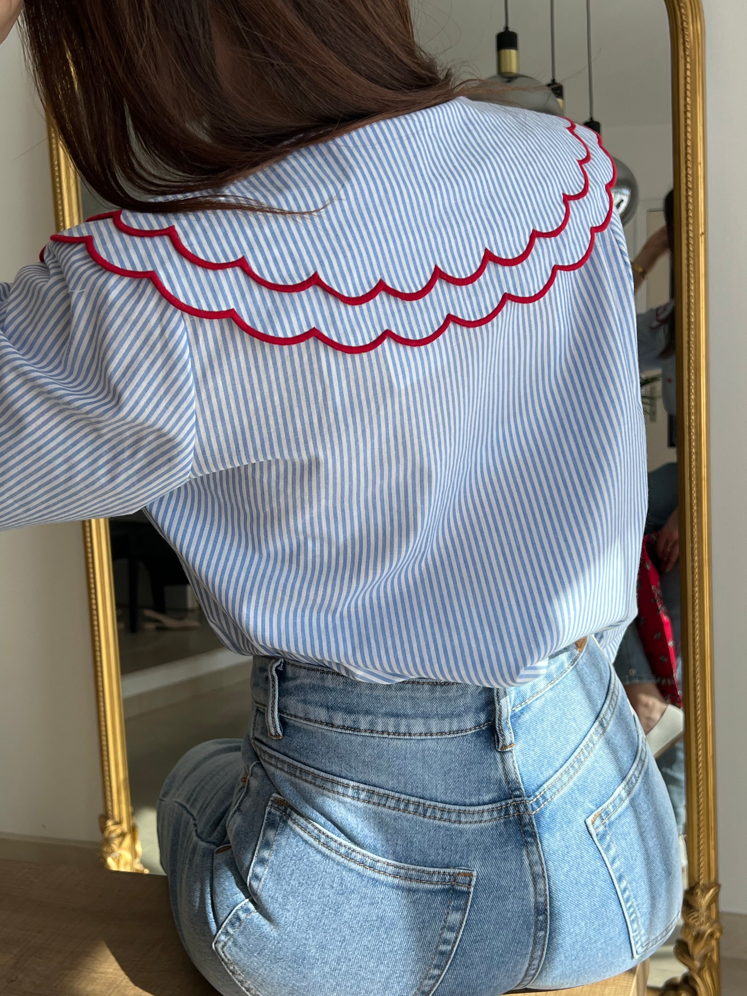 Chemise femme bleue à rayures avec col claudine, parfaite pour un look élégant et féminin. Ses manches longues et ses boutons rouges sur toute la longueur apportent une touche originale et raffinée. L’association des couleurs bleu, blanc et rouge crée un style chic et intemporel. Idéale pour une tenue moderne, aussi bien au bureau qu’au quotidien.