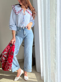 Chemise femme bleue à rayures avec col claudine, parfaite pour un look élégant et féminin. Ses manches longues et ses boutons rouges sur toute la longueur apportent une touche originale et raffinée. L’association des couleurs bleu, blanc et rouge crée un style chic et intemporel. Idéale pour une tenue moderne, aussi bien au bureau qu’au quotidien.