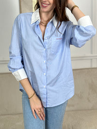 Chemise bleue femme aux rayures verticales délicates qui jouent entre le bleu et l'écru. Dotée de manches longues avec manchettes écrues et d'un col chemise classique, elle offre une allure intemporelle et élégante. Les boutons courent sur toute la longueur et aux poignets pour un ajustement parfait.&nbsp;
