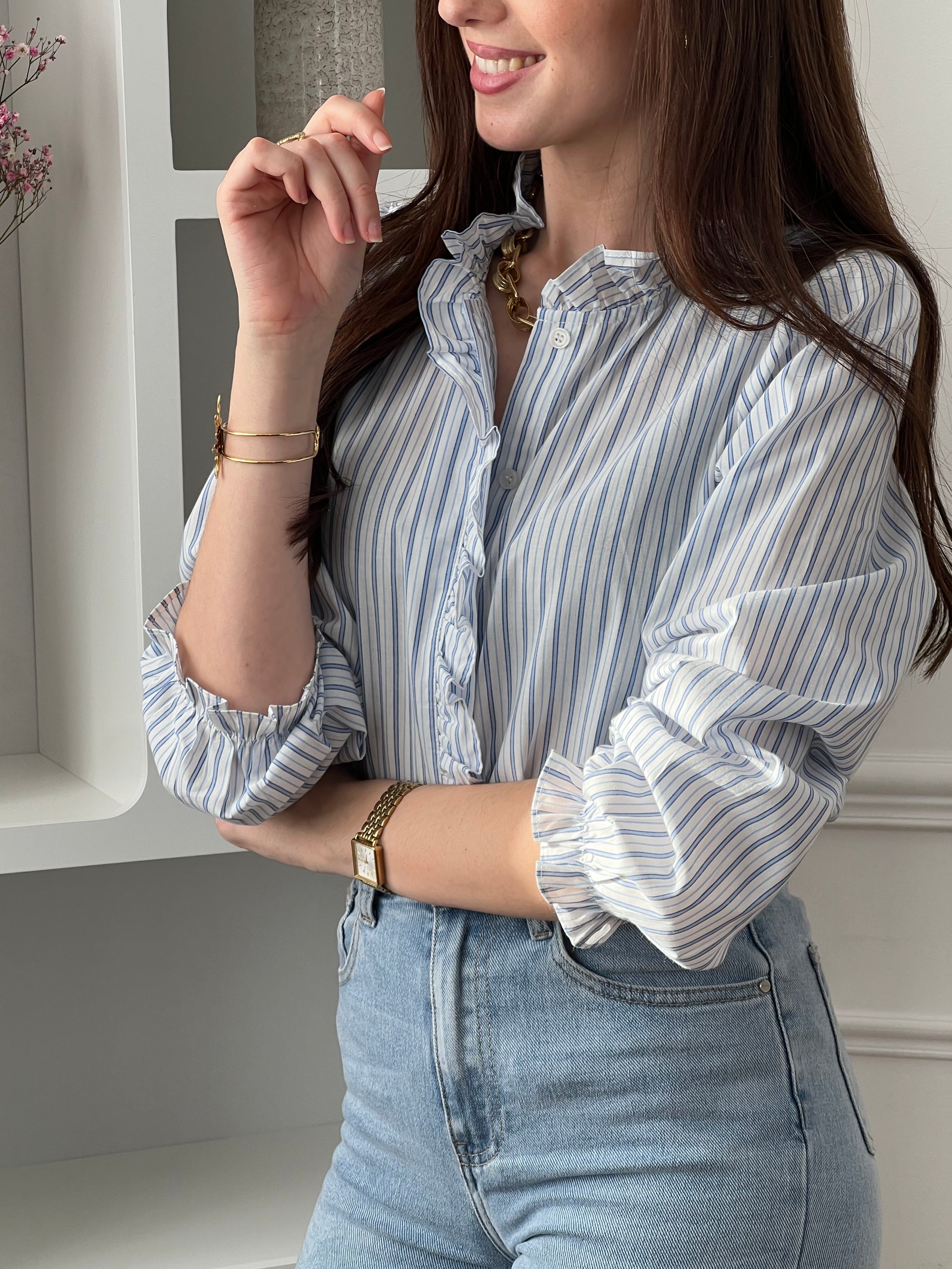 Adoptez cette chemise bleue et écrue femme, élégante et féminine. Dotée de manches longues, d’un col rond et de boutons sur toute la longueur, elle se distingue par ses volants au col et le long de la fermeture. Ses rayures verticales bleues et écrues apportent une touche raffinée et allongent la silhouette.