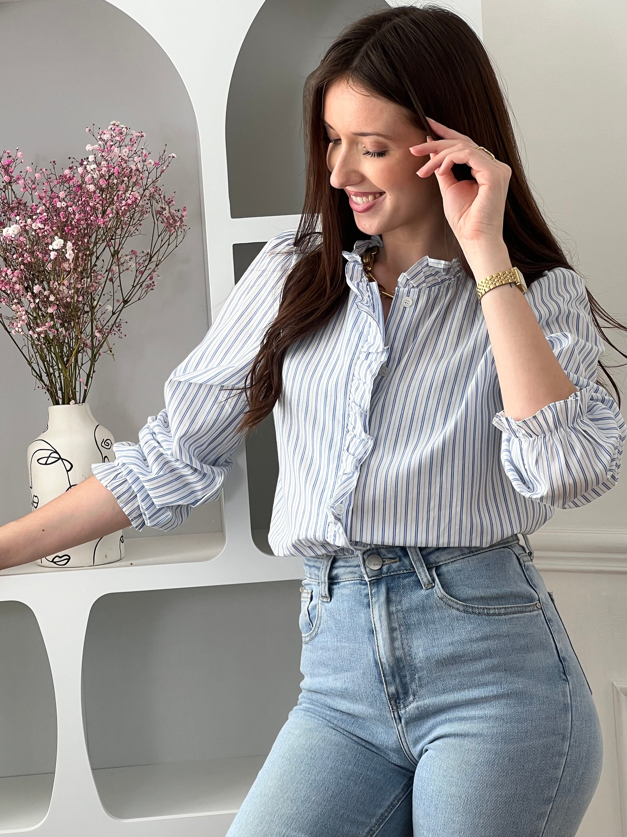 Adoptez cette chemise bleue et écrue femme, élégante et féminine. Dotée de manches longues, d’un col rond et de boutons sur toute la longueur, elle se distingue par ses volants au col et le long de la fermeture. Ses rayures verticales bleues et écrues apportent une touche raffinée et allongent la silhouette.