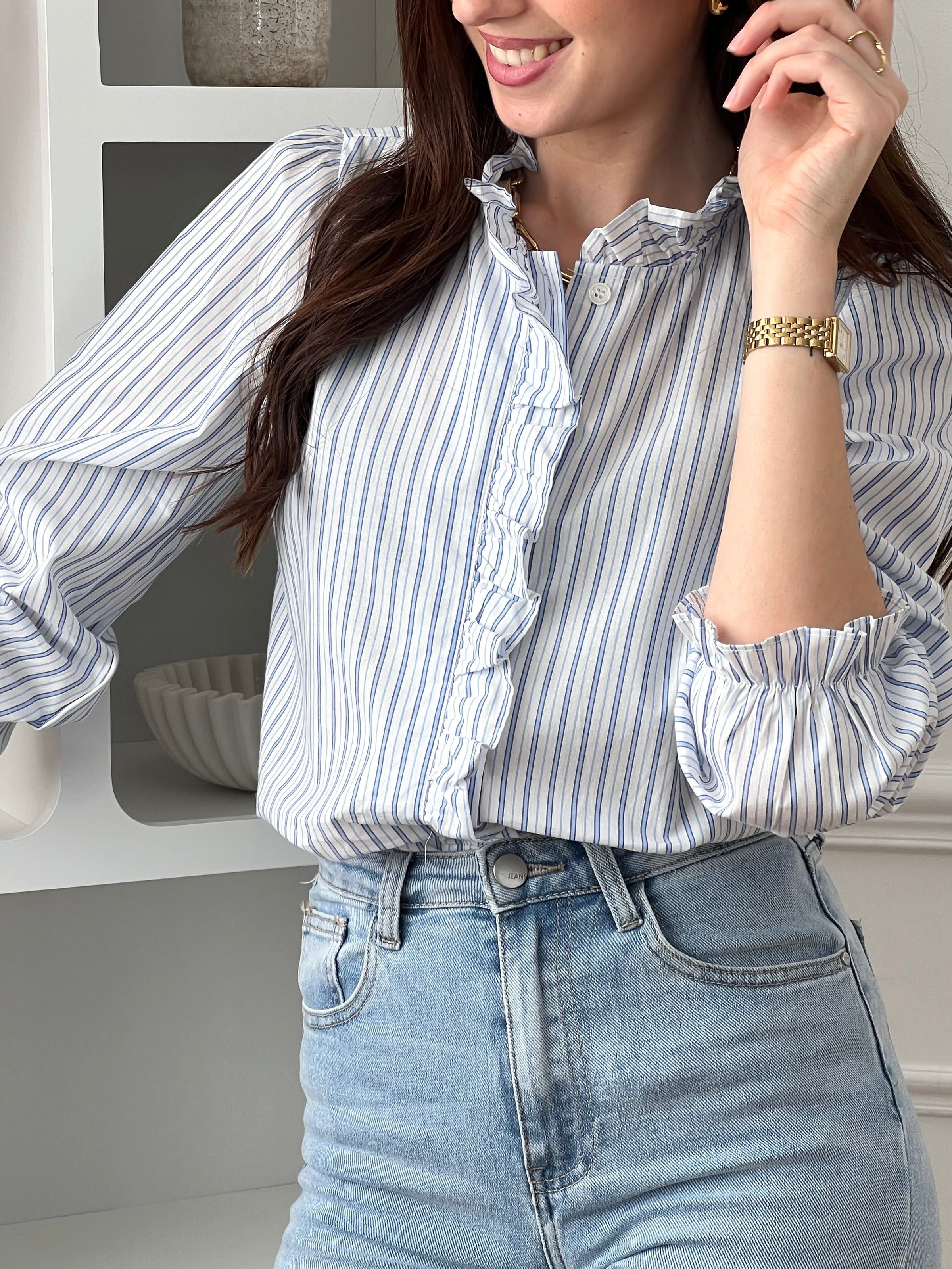 Adoptez cette chemise bleue et écrue femme, élégante et féminine. Dotée de manches longues, d’un col rond et de boutons sur toute la longueur, elle se distingue par ses volants au col et le long de la fermeture. Ses rayures verticales bleues et écrues apportent une touche raffinée et allongent la silhouette.