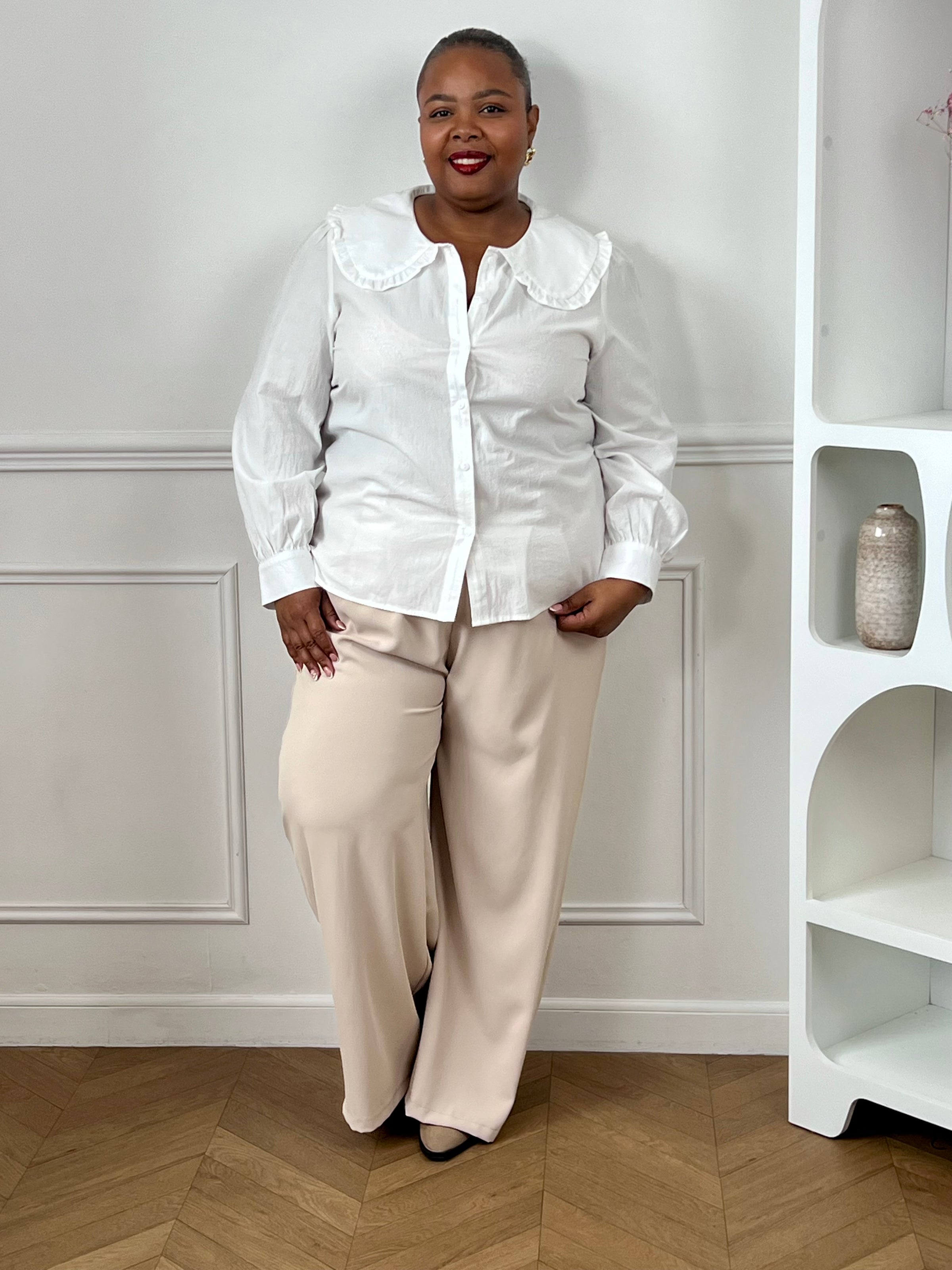 Chemise écrue grande taille femme en coton, portée avec un pantalon beige pour un look élégant.