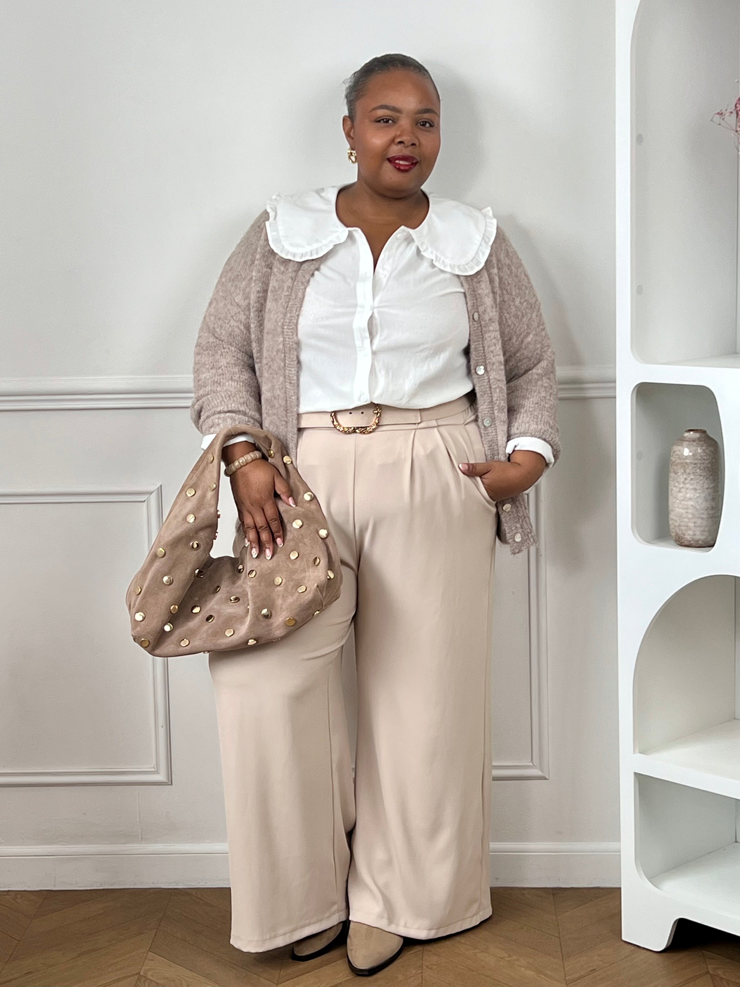 Chemise écrue à col claudine brodé associée à un pantalon beige et un sac marron.