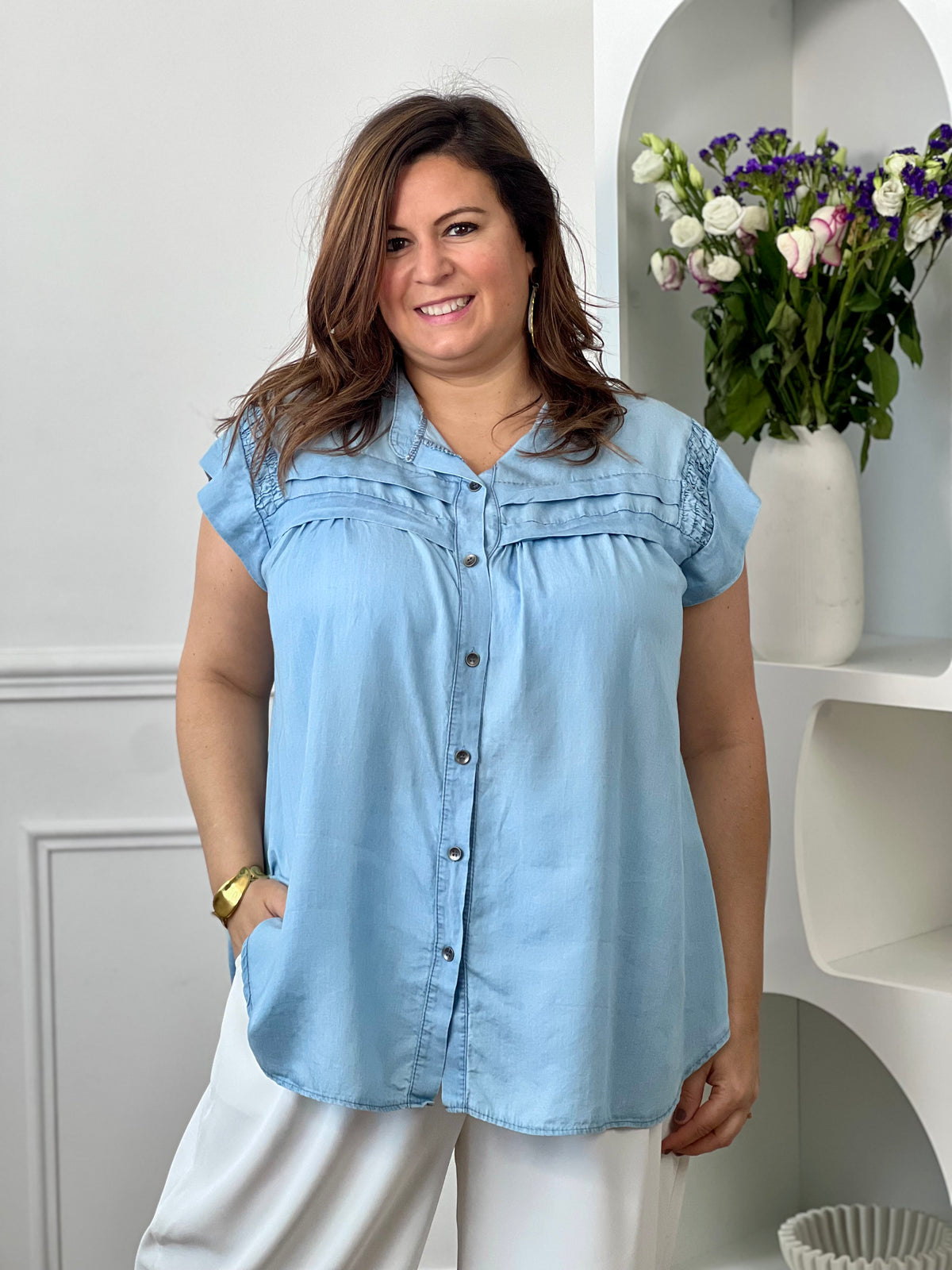Chemise grande taille femme sans manches, idéale pour une allure élégante et féminine. Dotée d’un col rond et de boutons gris sur toute la longueur, elle se distingue par ses volants aux épaules à l’avant et au dos qui apportent une touche raffinée. Fluide et agréable à porter, cette chemise aux tons bleu clair et gris est parfaite pour un look chic et tendance au quotidien.