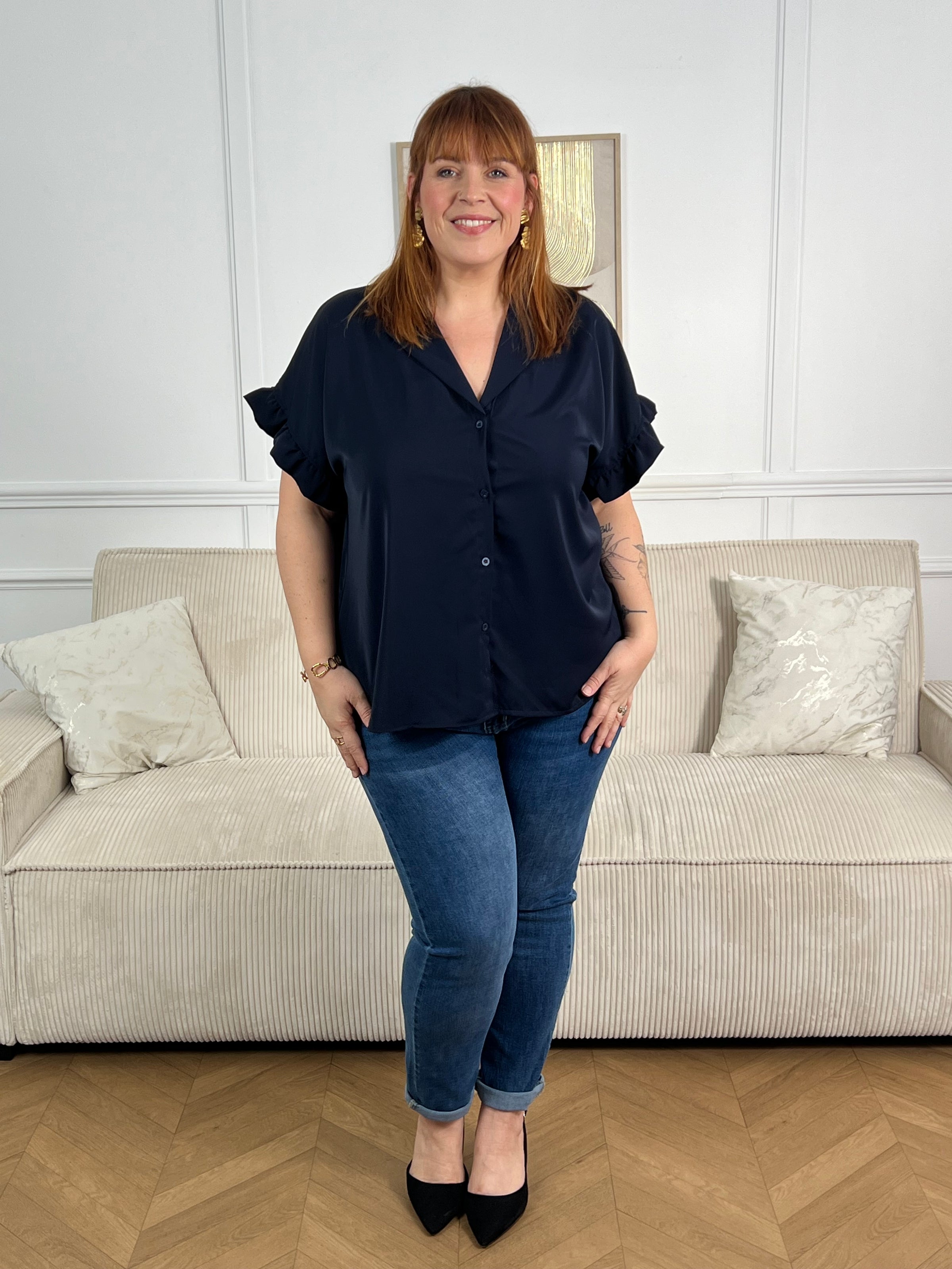 Chemise fluide en bleu marine pensée pour les grandes tailles. Manches courtes avec volants, col chemise et V, boutons échelonnés sur la longueur pour un ajustement sur mesure. Coupe généreuse et confortable, idéale pour vos tenues du quotidien comme pour les occasions plus habillées.