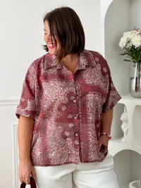 Adoptez un style chic et léger avec cette chemise grande taille femme aux motifs écrus élégants. Ses manches courtes, son col chemise classique et ses boutons sur toute la longueur en font une pièce facile à porter au quotidien. Légèrement transparente, elle apporte une touche féminine et aérienne, tandis que son association de bordeaux et d’écru offre un look tendance et raffiné.