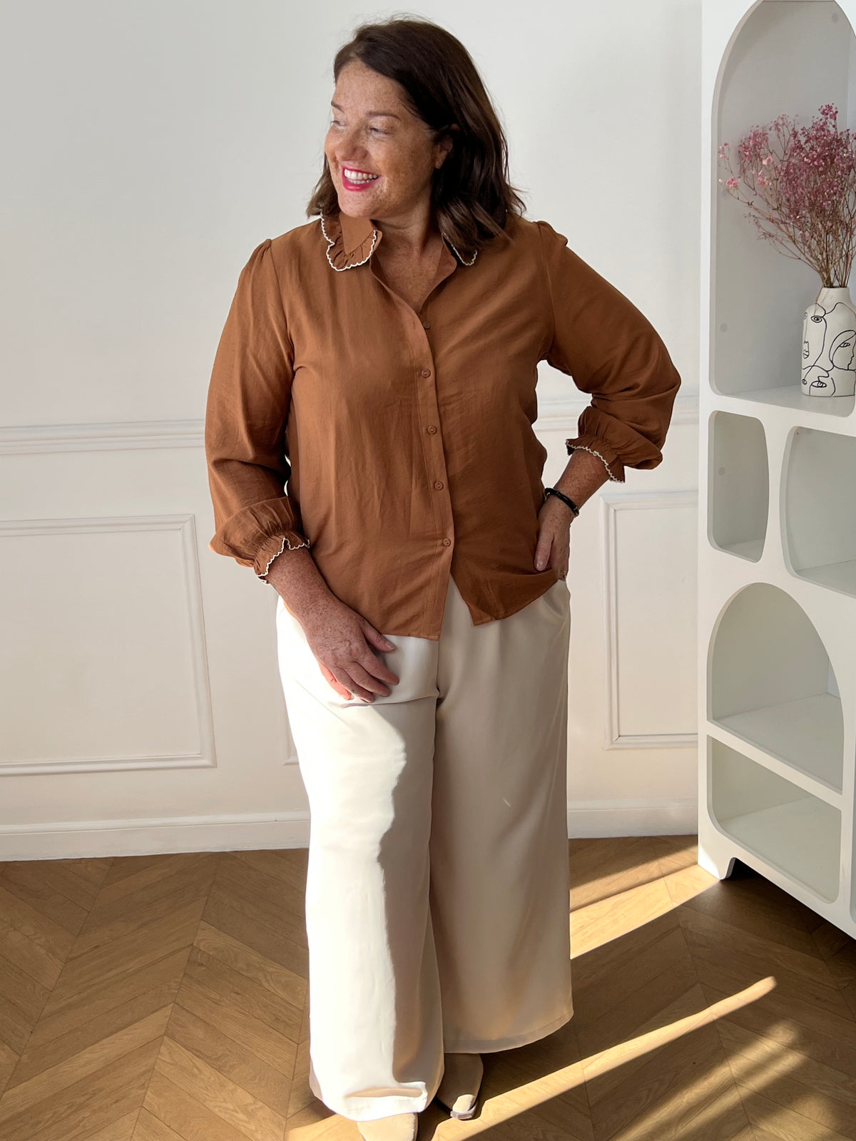 Chemise camel Salil grande taille portée de face sur un pantalon large beige, montrant la coupe ample et la fermeture boutonnée.