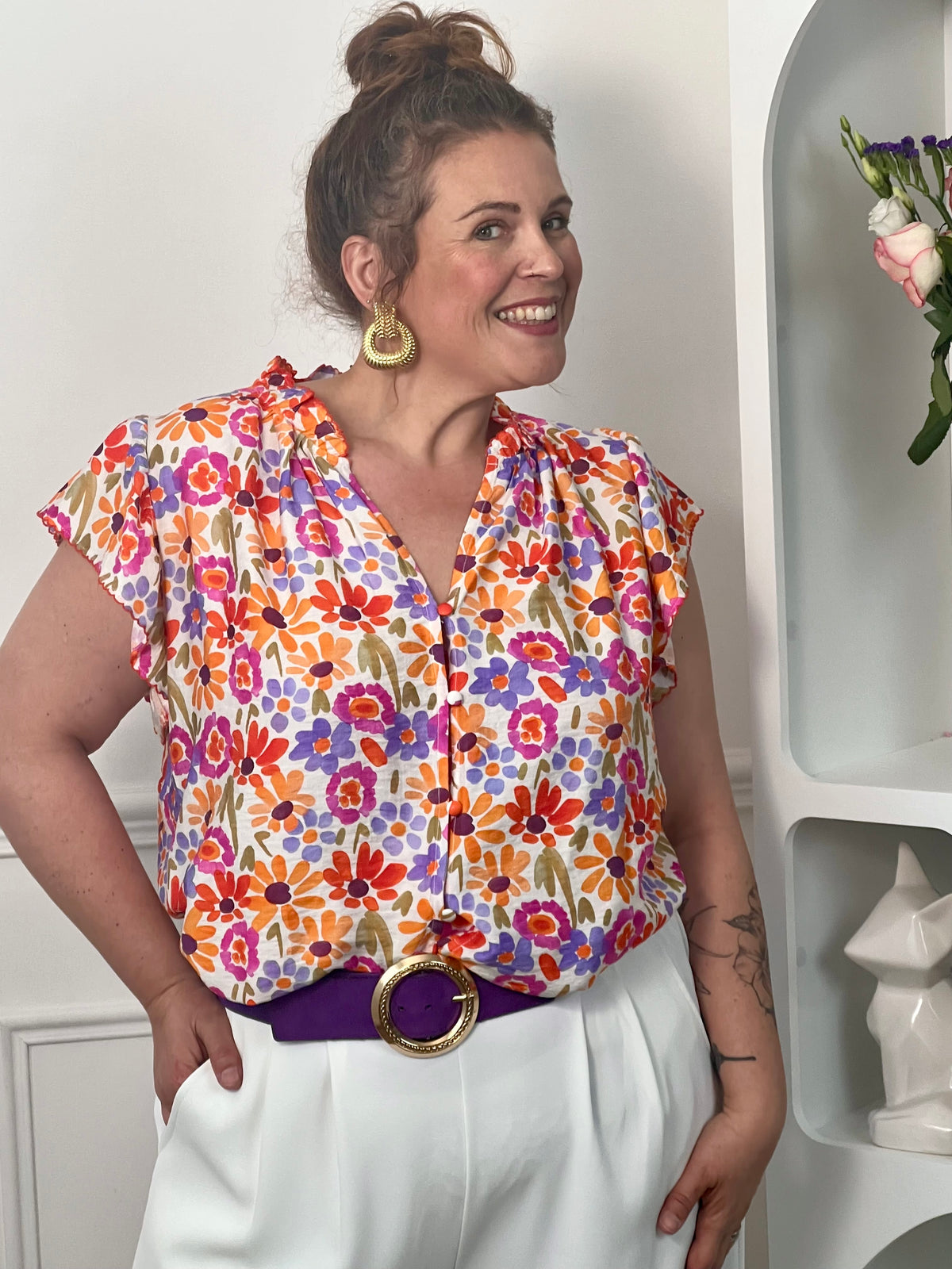 Chemise à motifs grande taille femme, parfaite pour un look féminin et tendance. Sans manches, avec un col V et des boutons sur toute la longueur, elle allie élégance et confort. Ses volants au niveau des épaules et du col apportent une touche raffinée, tandis que ses motifs fleurs aux tons orange, vert, violet, rose et écru illuminent la silhouette. Une chemise fluide idéale pour une tenue chic et estivale.