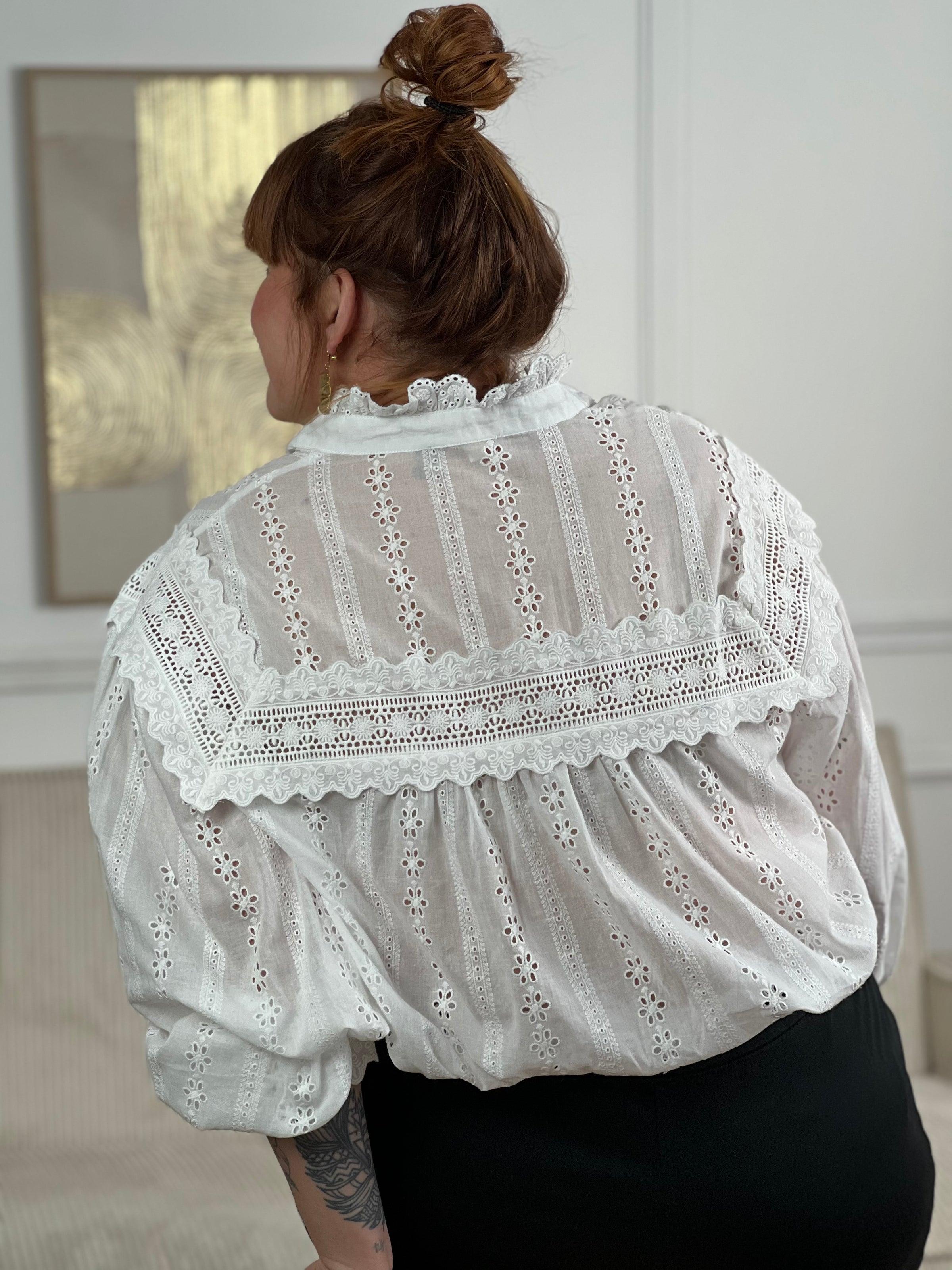 Chemise Angele en coton 100% pour les femmes grandes tailles. Manches bouffantes, col volant et broderie ajourée confèrent à cette pièce écrue une élégance intemporelle. Légèrement transparente, elle se porte avec aisance au quotidien comme en occasion.