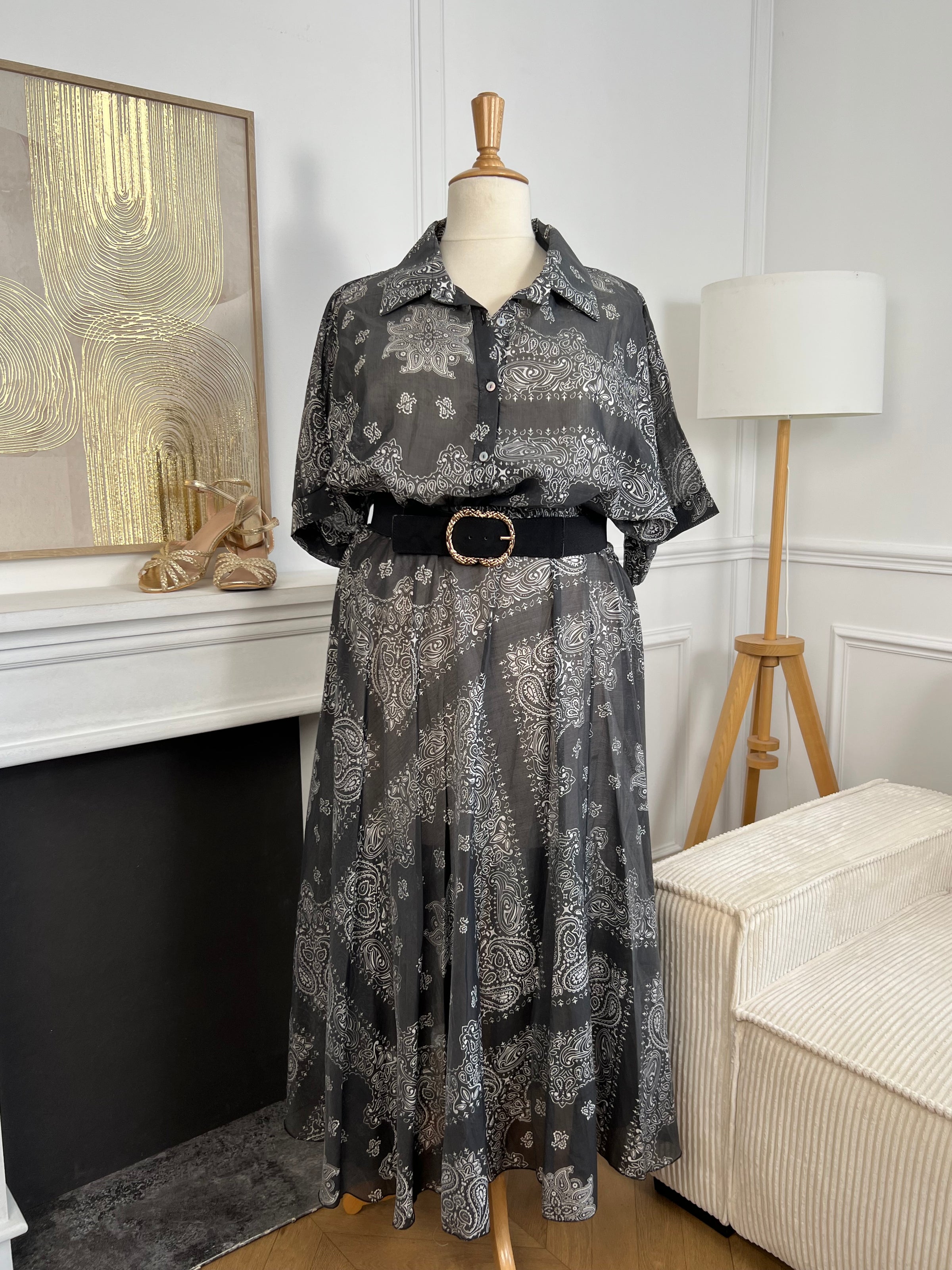 Adoptez un style chic et léger avec cette chemise grande taille femme aux motifs écrus élégants. Ses manches courtes, son col chemise classique et ses boutons sur toute la longueur en font une pièce facile à porter au quotidien. Légèrement transparente, elle apporte une touche féminine et aérienne, tandis que son association de gris et d’écru offre un look tendance et raffiné.