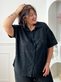 Chemise noire à sequins grande taille, idéale pour un look élégant et lumineux. Sa coupe manches courtes avec boutons sur la longueur offre confort et style, tandis que son effet ajouré apporte une touche moderne. Parfaite pour sublimer vos tenues de soirée ou du quotidien.