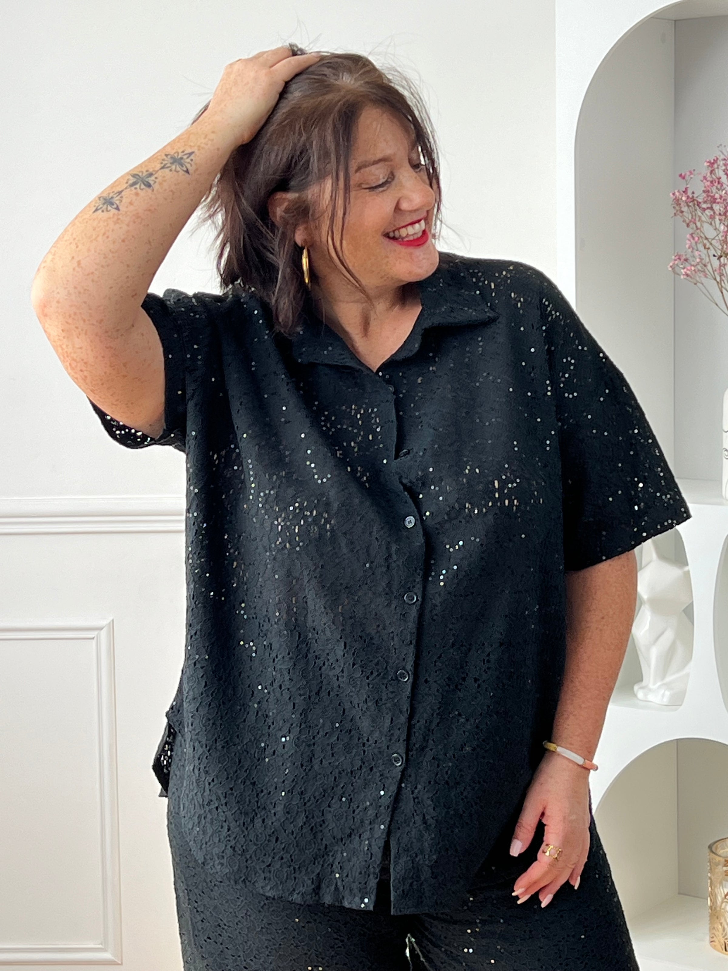 Chemise noire à sequins grande taille, idéale pour un look élégant et lumineux. Sa coupe manches courtes avec boutons sur la longueur offre confort et style, tandis que son effet ajouré apporte une touche moderne. Parfaite pour sublimer vos tenues de soirée ou du quotidien.