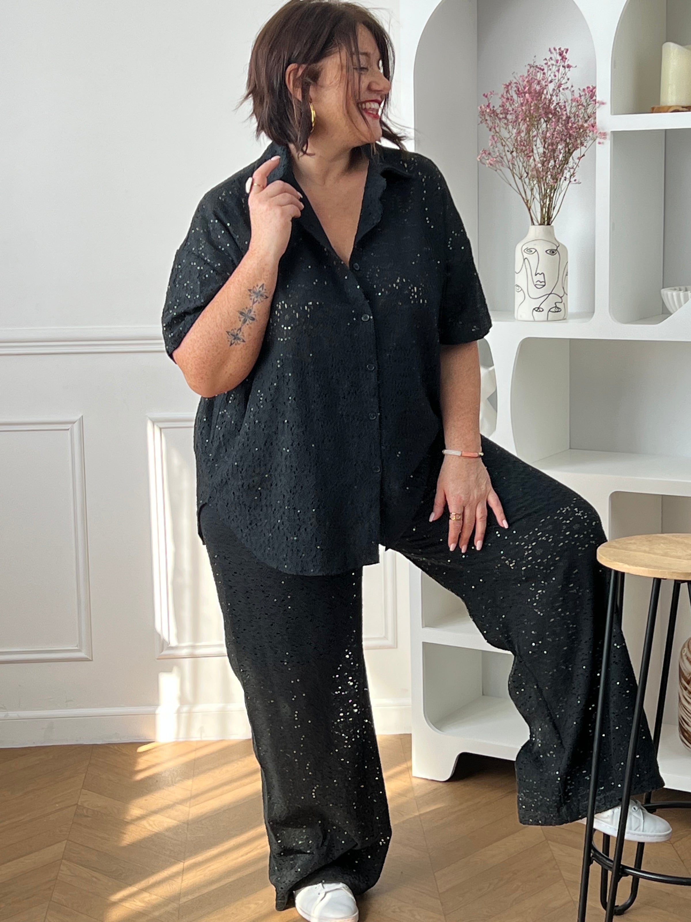 Chemise noire à sequins grande taille, idéale pour un look élégant et lumineux. Sa coupe manches courtes avec boutons sur la longueur offre confort et style, tandis que son effet ajouré apporte une touche moderne. Parfaite pour sublimer vos tenues de soirée ou du quotidien.
