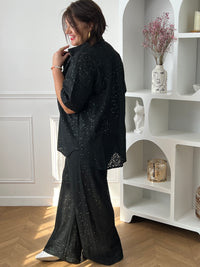 Chemise noire à sequins grande taille, idéale pour un look élégant et lumineux. Sa coupe manches courtes avec boutons sur la longueur offre confort et style, tandis que son effet ajouré apporte une touche moderne. Parfaite pour sublimer vos tenues de soirée ou du quotidien.