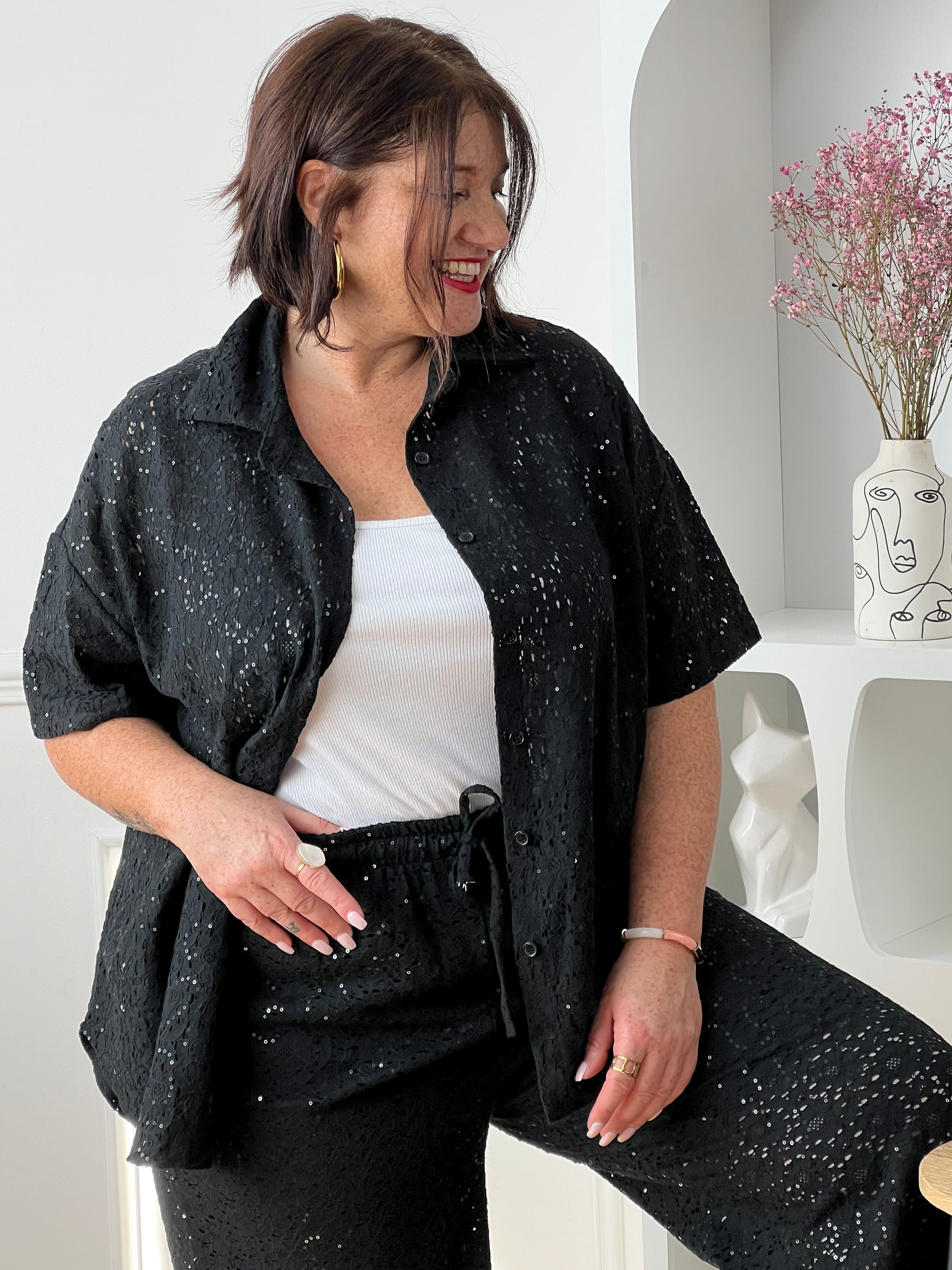Chemise noire à sequins grande taille, idéale pour un look élégant et lumineux. Sa coupe manches courtes avec boutons sur la longueur offre confort et style, tandis que son effet ajouré apporte une touche moderne. Parfaite pour sublimer vos tenues de soirée ou du quotidien.