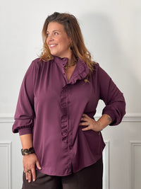 Chemise prune Johana grande taille portée de face sur un pantalon marron, montrant sa coupe ample et son bas arrondi.