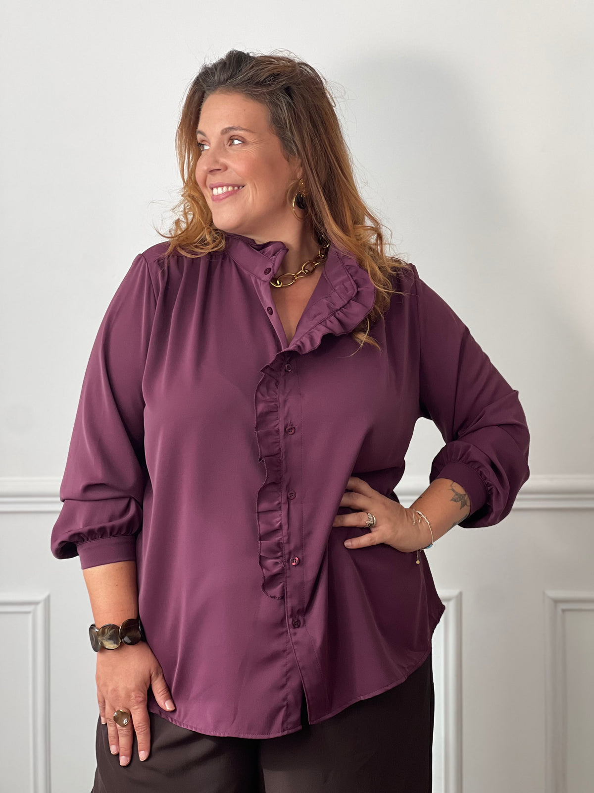 Chemise prune Johana grande taille portée de face sur un pantalon marron, montrant sa coupe ample et son bas arrondi.