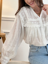 Chemise Angele en coton 100% pour les femmes. Manches bouffantes, col volant et broderie ajourée confèrent à cette pièce écrue une élégance intemporelle. Légèrement transparente, elle se porte avec aisance au quotidien comme en occasion.