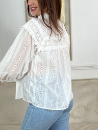 Chemise Angele en coton 100% pour les femmes. Manches bouffantes, col volant et broderie ajourée confèrent à cette pièce écrue une élégance intemporelle. Légèrement transparente, elle se porte avec aisance au quotidien comme en occasion.